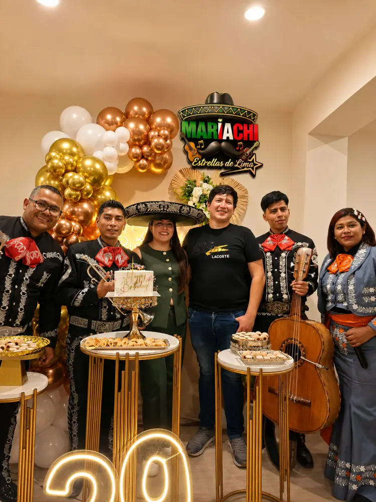 Cumpleaños con globos dorados, mesa de dulces y el grupo junto al festejado