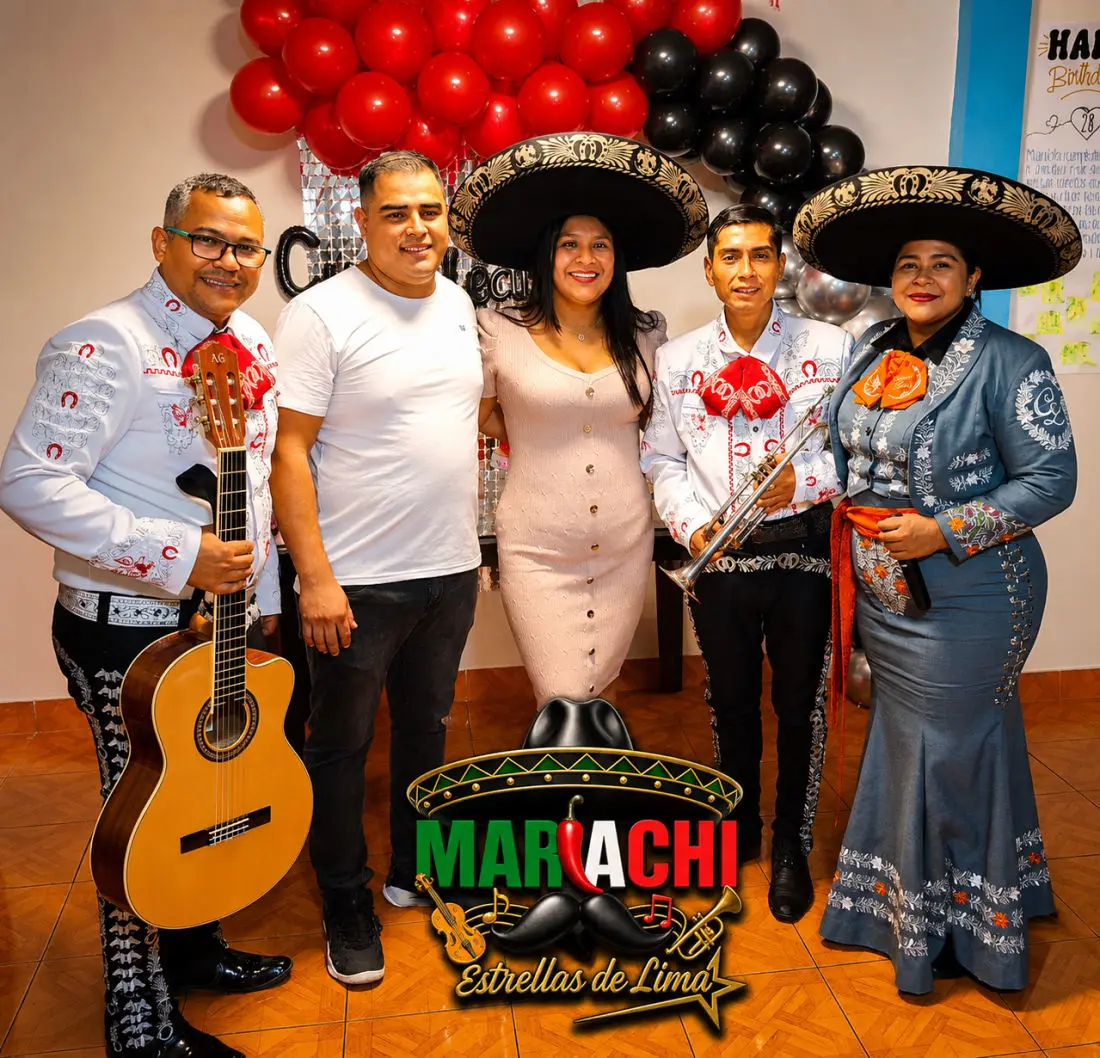 El grupo en traje de charro blanco junto a clientes en un cumpleaños con globos rojos y negros